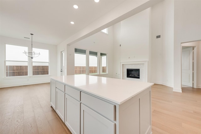 3231 Fisher Rd, Rockwall, TX 75032 - kitchen featuring light wood finished floors, a kitchen island, recessed lighting, a chandelier, and a glass covered fireplace