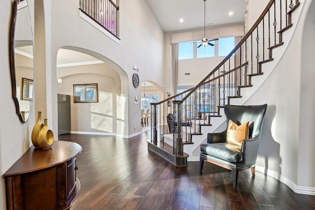 foyer entrance with ceiling fan, hardwood / wood-style floors, a high ceiling, and ornamental molding