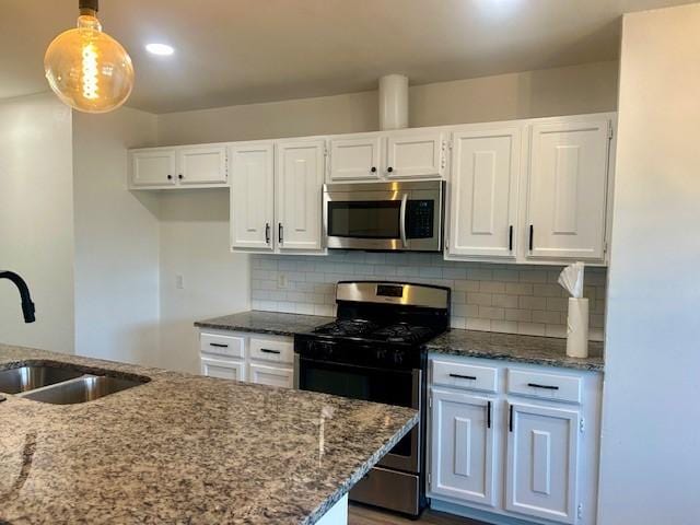 kitchen with stainless steel appliances, white cabinetry, hanging light fixtures, and sink