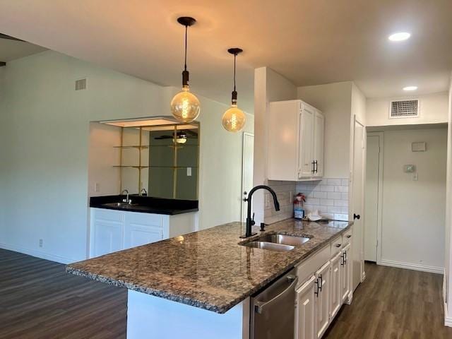 kitchen with white cabinetry, decorative light fixtures, dark stone countertops, stainless steel dishwasher, and sink