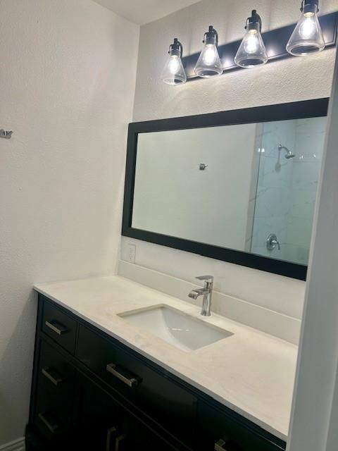 bathroom with vanity and a tile shower