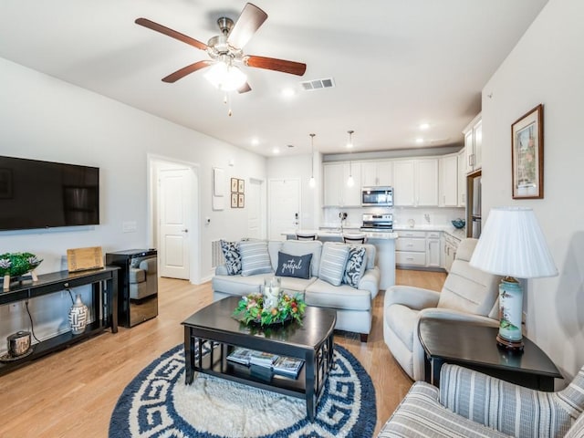 living room with light hardwood / wood-style floors and ceiling fan