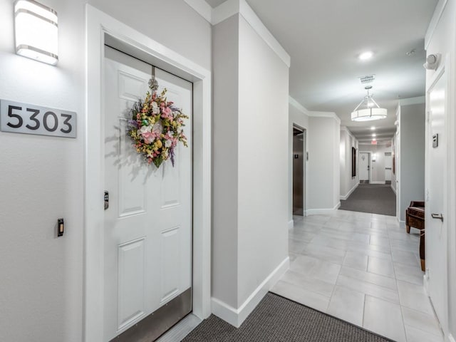 hallway with light tile patterned floors and crown molding