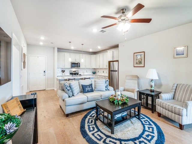 living room with ceiling fan and light hardwood / wood-style flooring