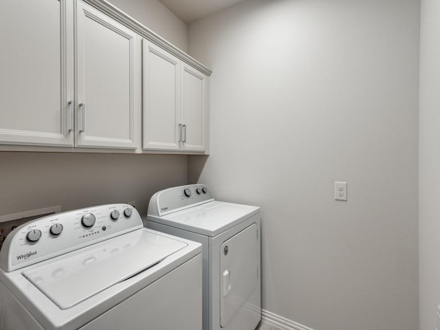 clothes washing area featuring cabinets and separate washer and dryer