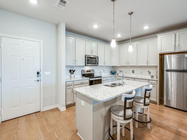 kitchen featuring sink, white cabinetry, stainless steel appliances, and a kitchen island with sink