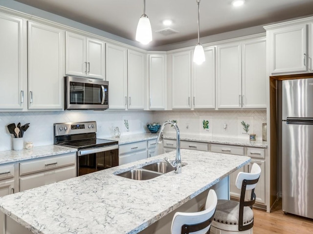 kitchen featuring pendant lighting, sink, decorative backsplash, appliances with stainless steel finishes, and white cabinetry