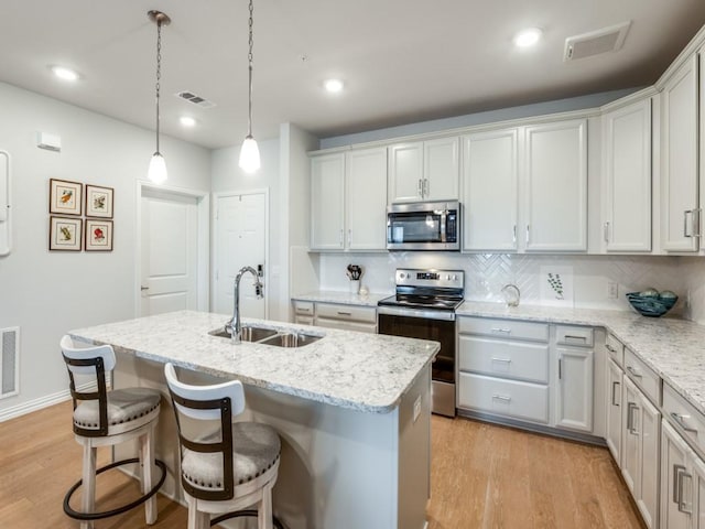 kitchen featuring backsplash, sink, stainless steel appliances, and an island with sink