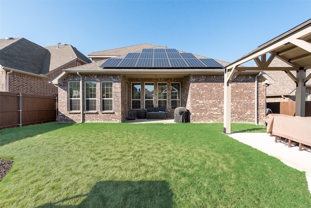 rear view of house with a lawn, solar panels, and a patio