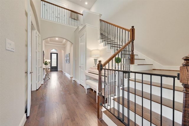 entryway featuring a towering ceiling, dark hardwood / wood-style flooring, and ornamental molding