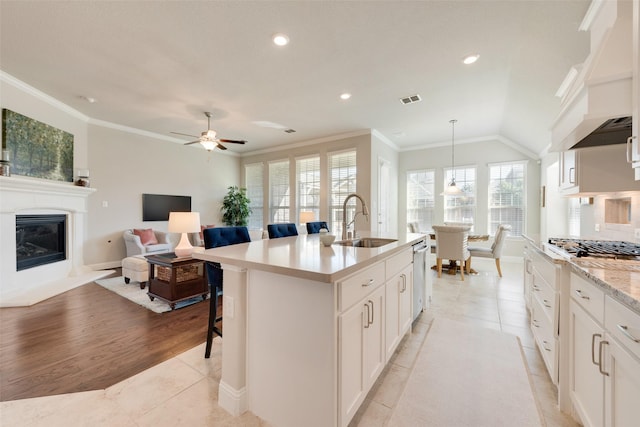 kitchen featuring white cabinetry, sink, pendant lighting, a breakfast bar, and a center island with sink