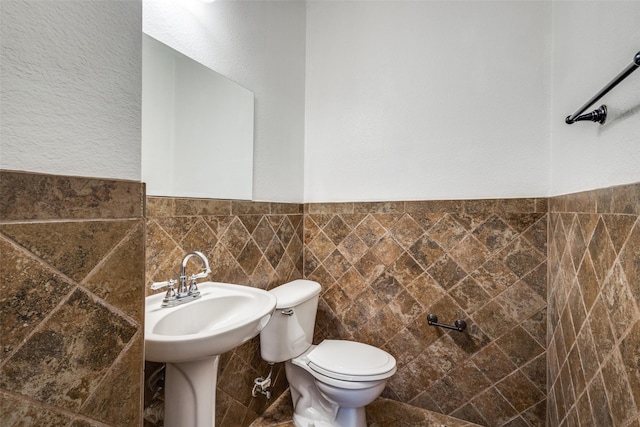 bathroom featuring toilet and tile walls