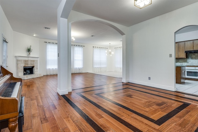 unfurnished living room featuring a fireplace, light hardwood / wood-style flooring, and a notable chandelier