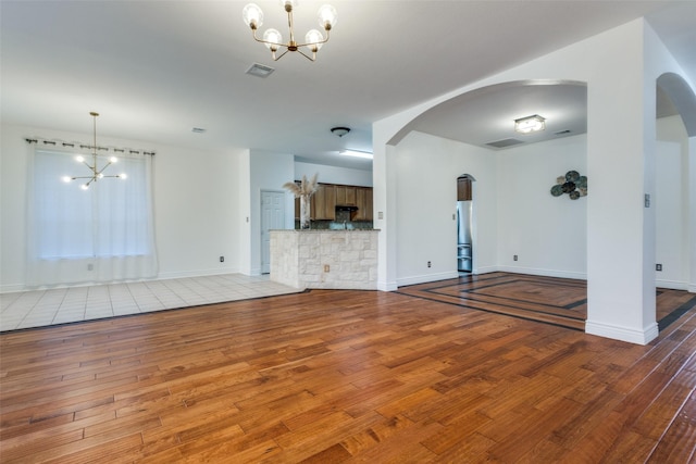 unfurnished living room featuring a notable chandelier and light hardwood / wood-style flooring