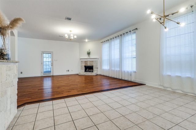 unfurnished living room with light tile patterned floors, a notable chandelier, and a fireplace