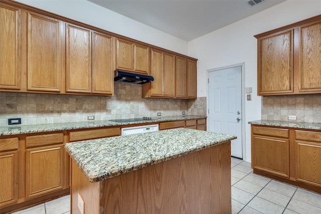 kitchen featuring light tile patterned flooring, light stone countertops, backsplash, and a kitchen island