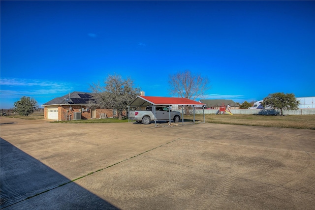 view of vehicle parking featuring a garage, a carport, and a lawn