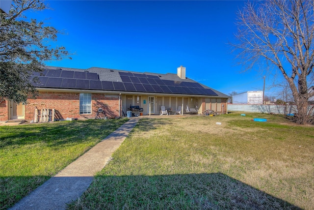 back of property featuring a lawn and solar panels