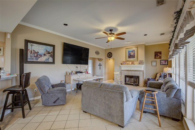 tiled living room with a tile fireplace, ceiling fan, and ornamental molding