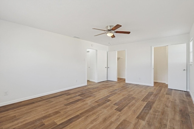 unfurnished bedroom with hardwood / wood-style flooring, ceiling fan, a walk in closet, and a closet