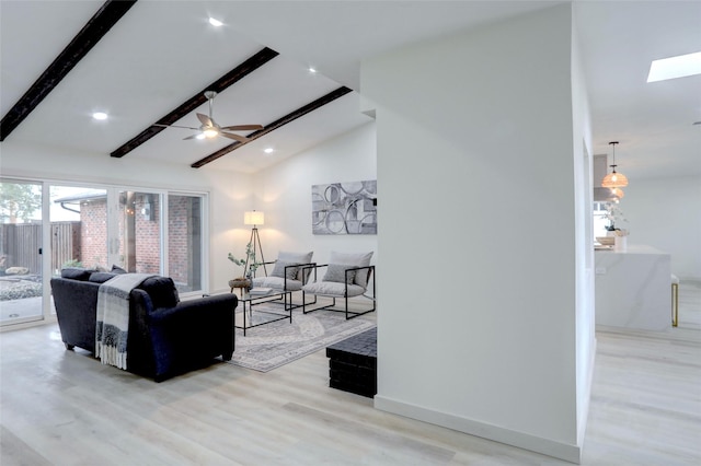 living room with light wood-type flooring, ceiling fan, and vaulted ceiling with skylight