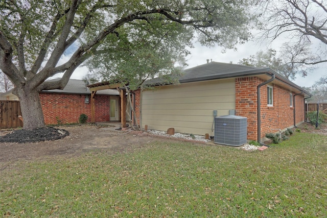 rear view of house featuring central air condition unit and a yard