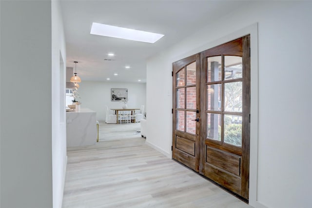 interior space featuring french doors, a skylight, and light hardwood / wood-style floors