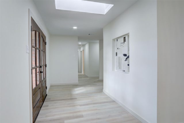 hall featuring a skylight and light hardwood / wood-style flooring