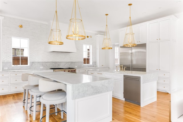 kitchen with white cabinets, appliances with stainless steel finishes, a kitchen island, and hanging light fixtures