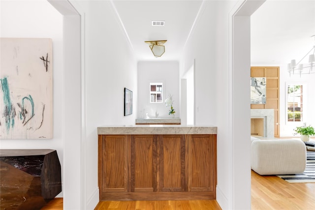 bar with a notable chandelier and light hardwood / wood-style floors