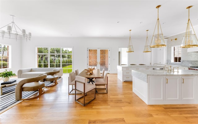 kitchen featuring light stone countertops, sink, decorative light fixtures, light hardwood / wood-style flooring, and white cabinets