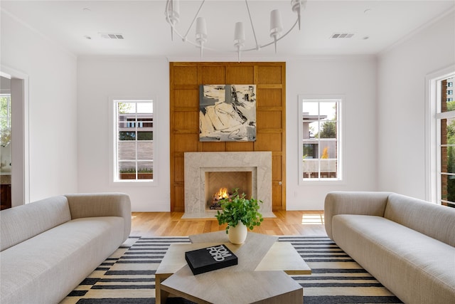 living room with light hardwood / wood-style floors, a fireplace, a healthy amount of sunlight, and ornamental molding