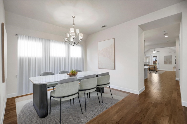 dining area featuring dark hardwood / wood-style flooring and ceiling fan with notable chandelier