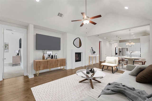 living room with vaulted ceiling, dark hardwood / wood-style flooring, and ceiling fan with notable chandelier