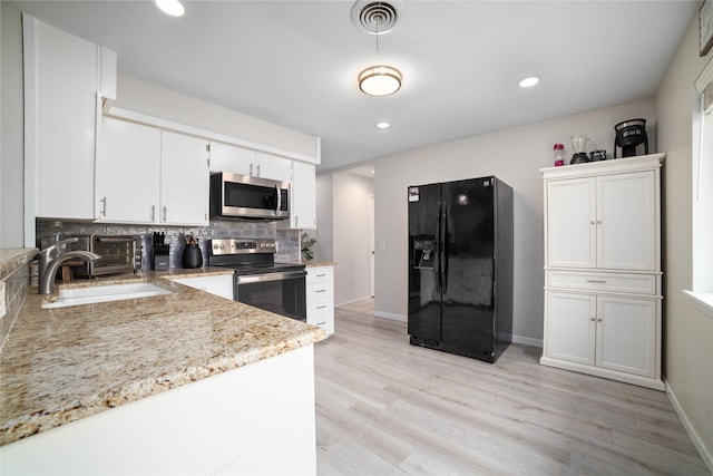 kitchen featuring appliances with stainless steel finishes, backsplash, sink, light hardwood / wood-style flooring, and white cabinetry