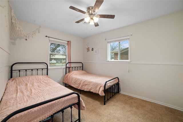 bedroom with ceiling fan, light colored carpet, and multiple windows