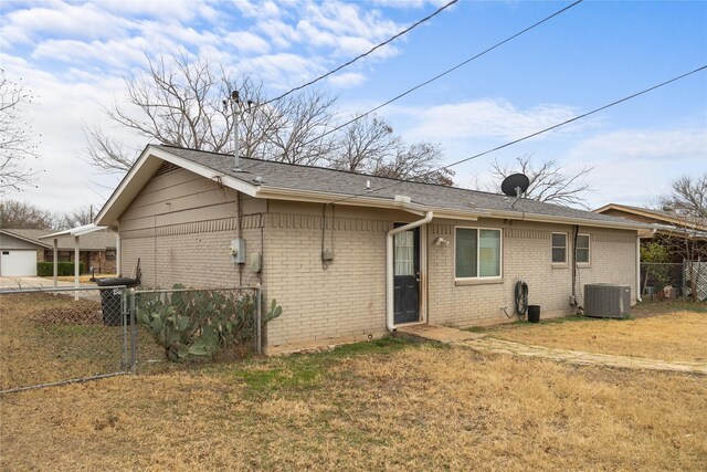 rear view of house with cooling unit and a yard