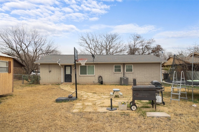 back of property featuring a lawn, cooling unit, and a trampoline