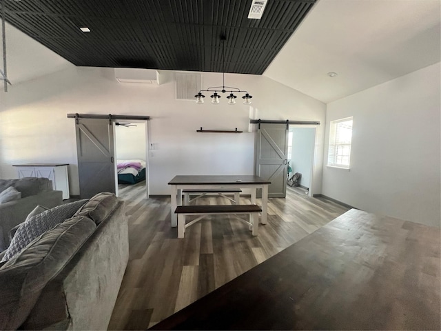 living room with lofted ceiling, a barn door, and hardwood / wood-style floors