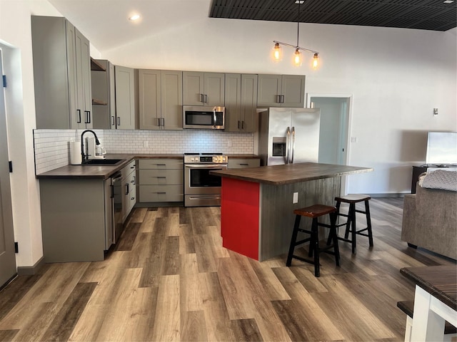 kitchen featuring stainless steel appliances, gray cabinets, sink, and hanging light fixtures