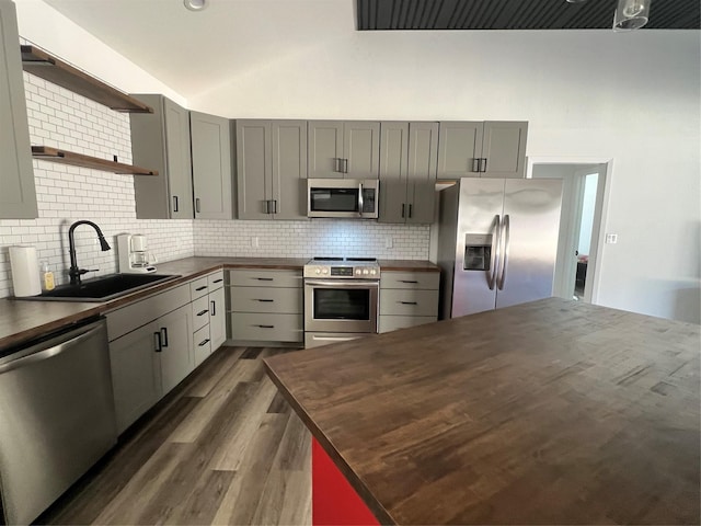 kitchen featuring lofted ceiling, sink, gray cabinetry, stainless steel appliances, and tasteful backsplash