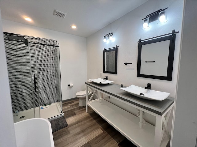 bathroom featuring wood-type flooring, toilet, a shower with door, and vanity