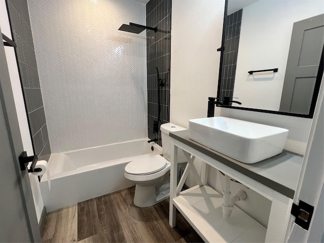 bathroom with tiled shower / bath, toilet, and hardwood / wood-style floors