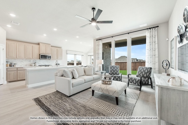 living room featuring ceiling fan, light hardwood / wood-style floors, and vaulted ceiling