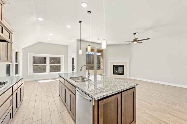 kitchen featuring a sink, open floor plan, hanging light fixtures, stainless steel dishwasher, and a tiled fireplace