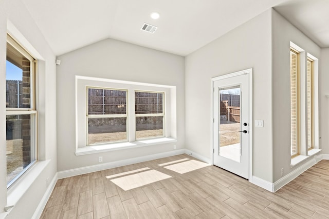 interior space with vaulted ceiling, light wood-type flooring, visible vents, and baseboards