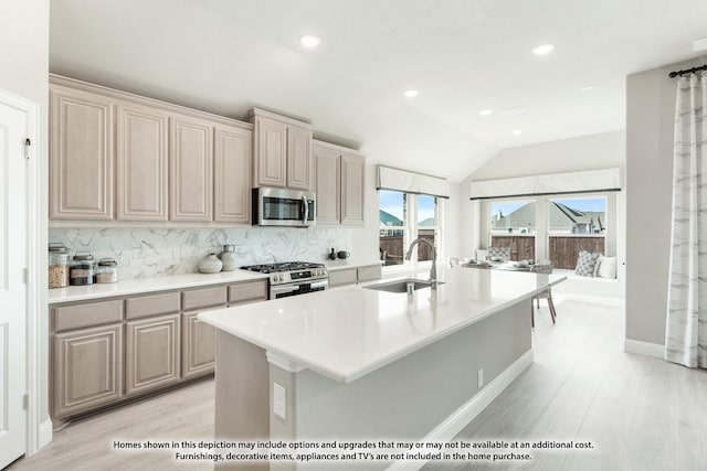 kitchen with lofted ceiling, sink, an island with sink, tasteful backsplash, and stainless steel appliances