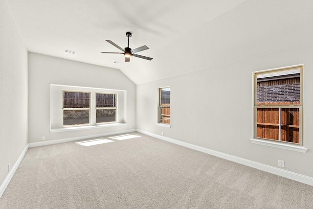 empty room featuring baseboards, visible vents, a ceiling fan, lofted ceiling, and carpet