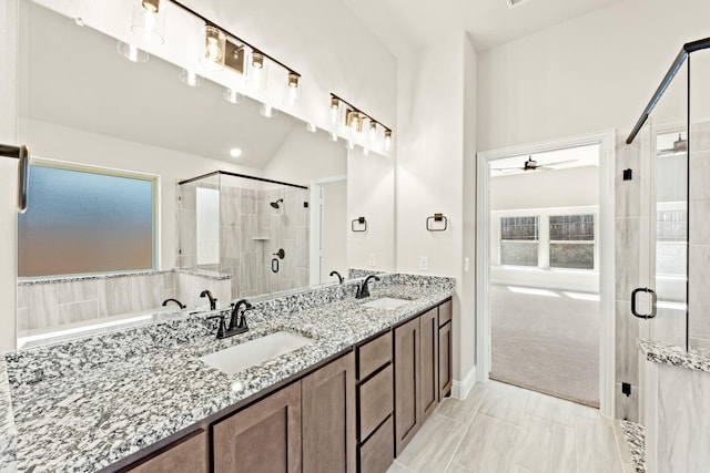 bathroom featuring vaulted ceiling, a sink, a shower stall, and double vanity