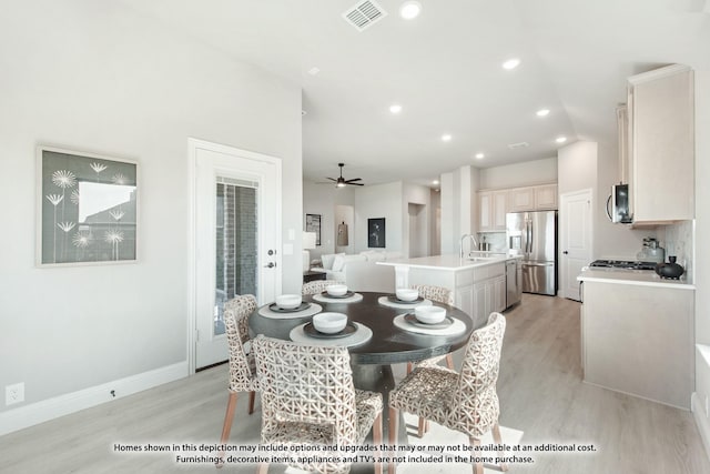 dining area with ceiling fan, sink, and light hardwood / wood-style flooring